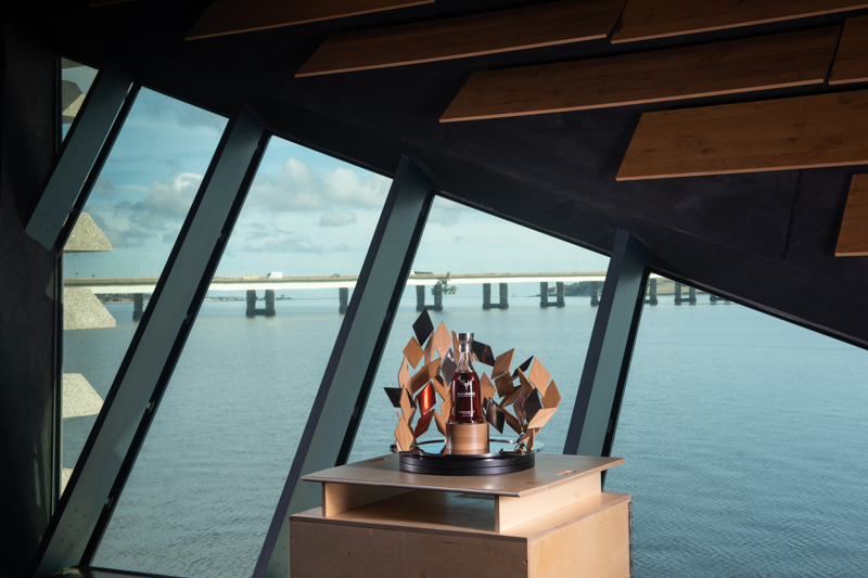 Bottle and sculpture on display in front of a window overlooking the River Tay